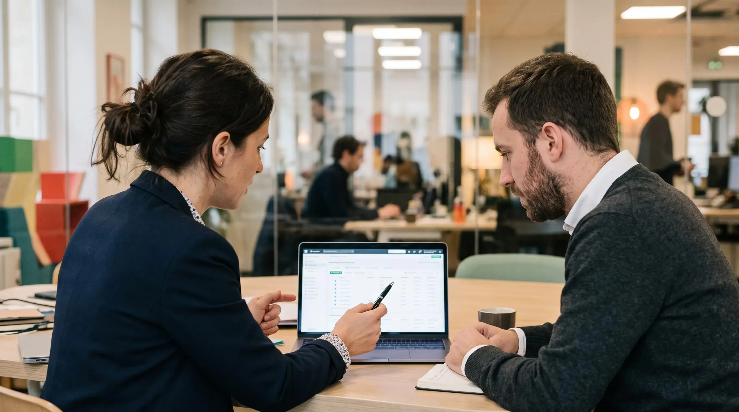 Une consultante explique la structure d'un compte publicitaire à son client devant un ordinateur portable.