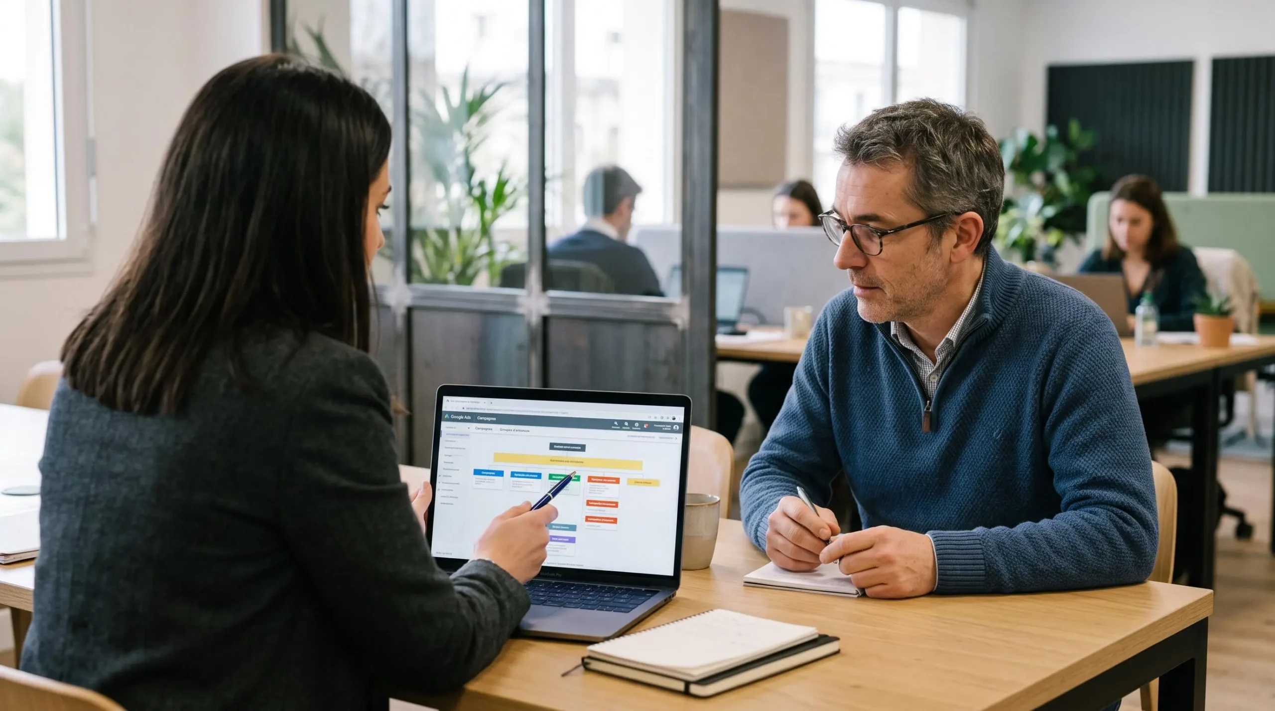 Une consultante explique la structure d'un compte publicitaire à son client devant un ordinateur portable.